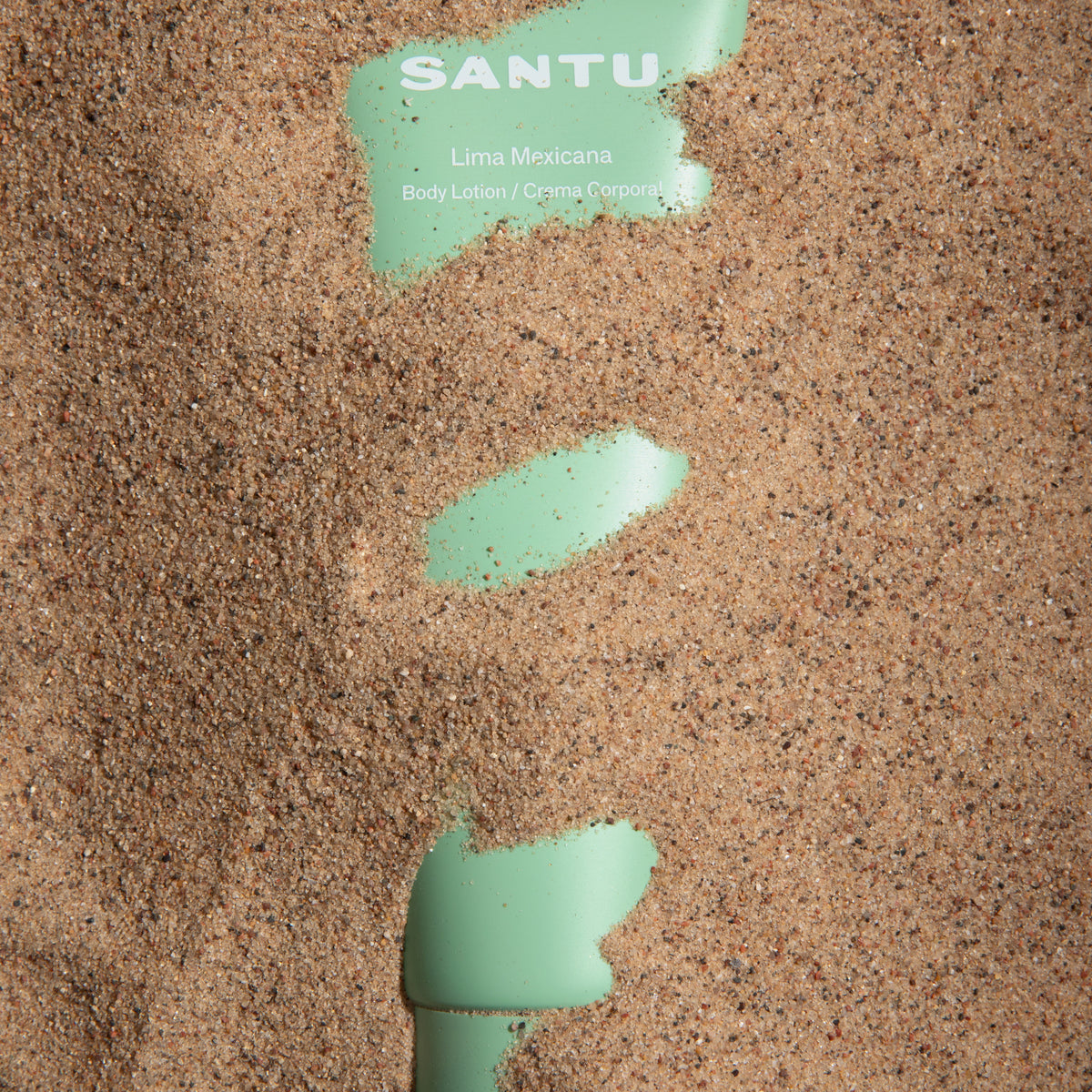 Green body lotion smear on sand with 'SANTU' branding.