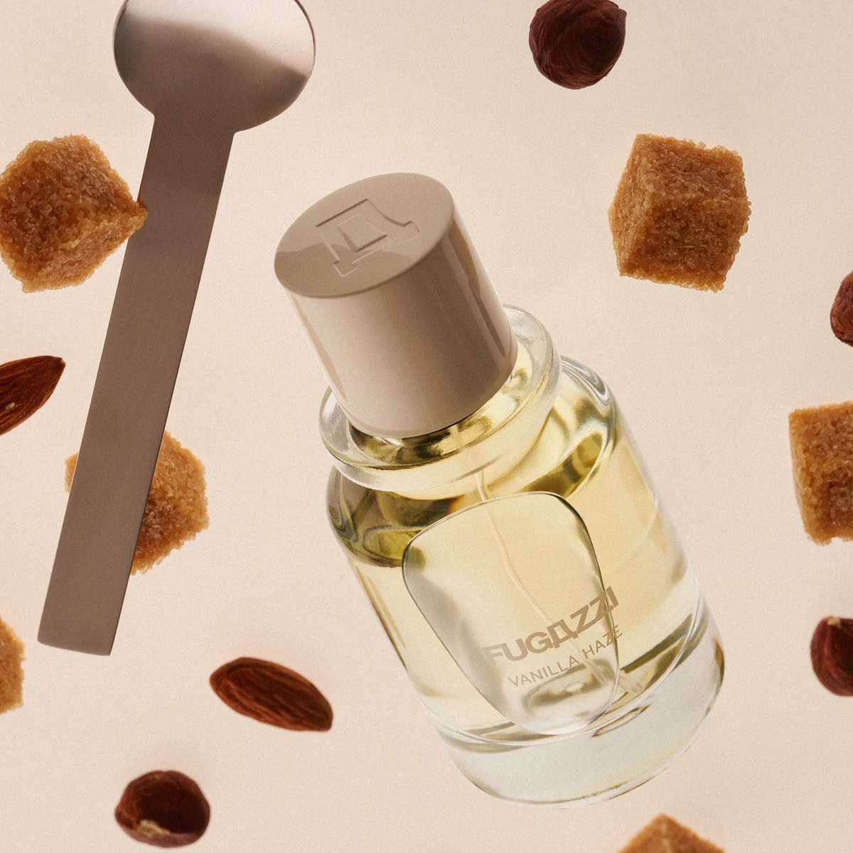 fugazzi vanilla haze perfume bottle with brown sugar cubes almonds and a spoon around it.