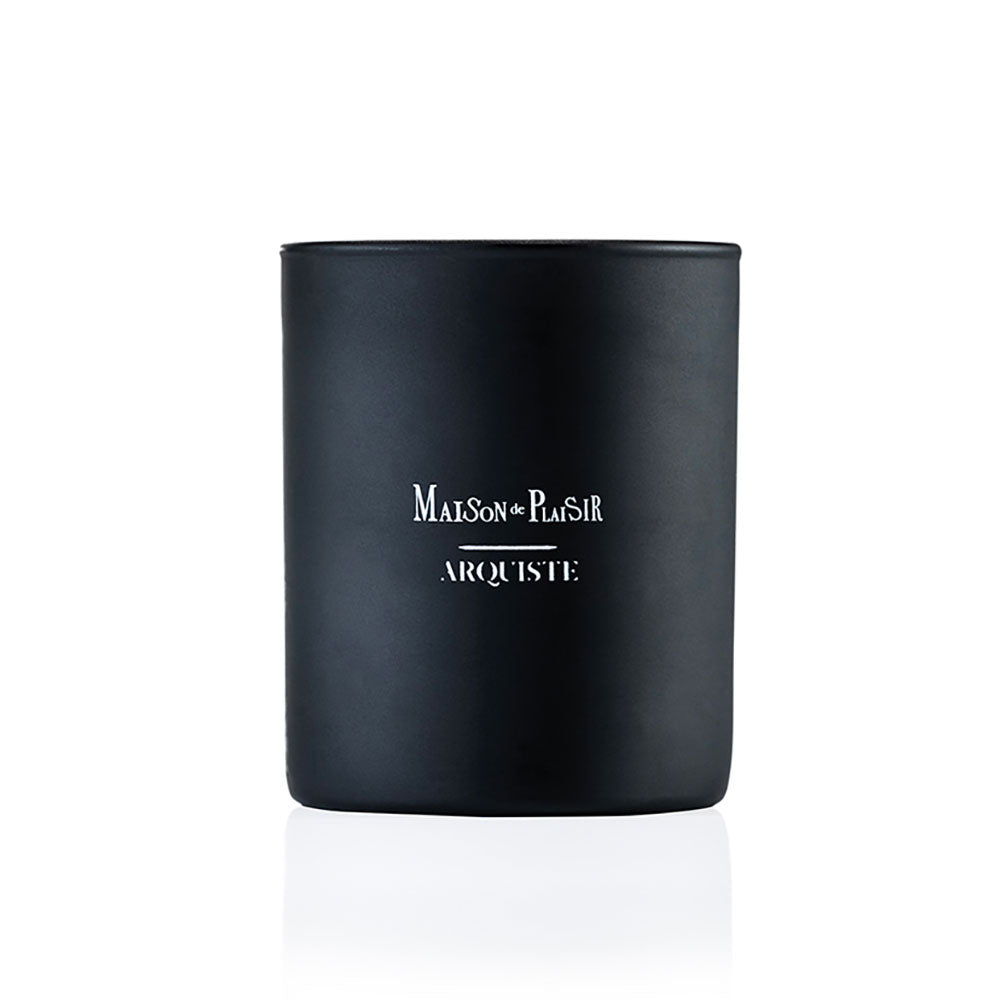 A black candle with a white label reading 'MAISON DE PLAISIR ARQUISTE'.