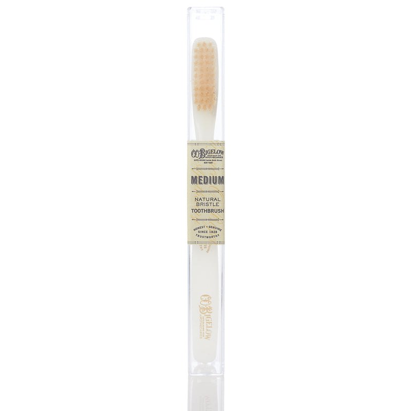A medium ivory toothbrush with natural bristles, displayed in front of a clear packaging tube.