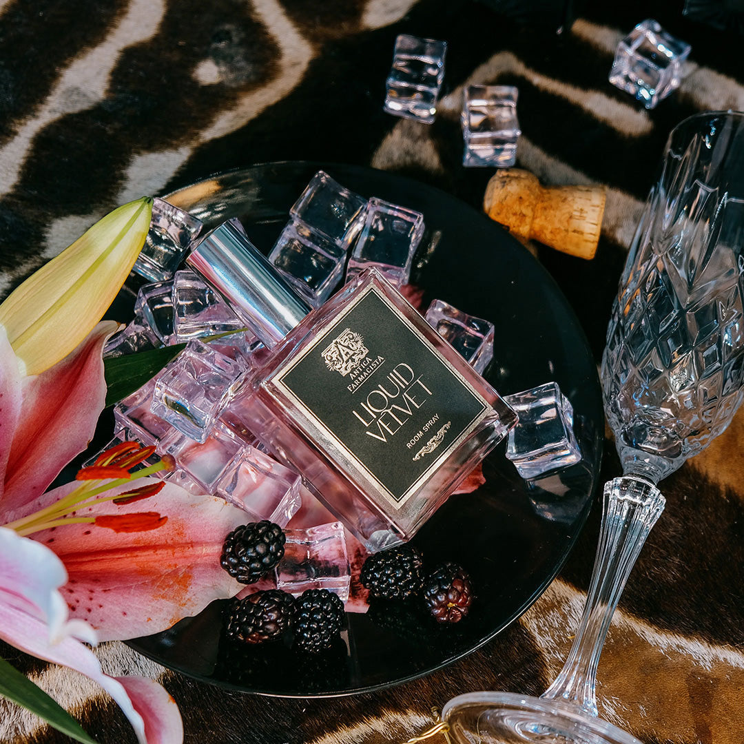 Liquid velvet bottle on a plate with a flower, ice, and blackberries