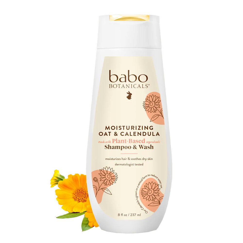 A pump bottle of Babo Botanicals Smoothing Berry & Primrose Shampoo & Wash next to yellow flowers.
