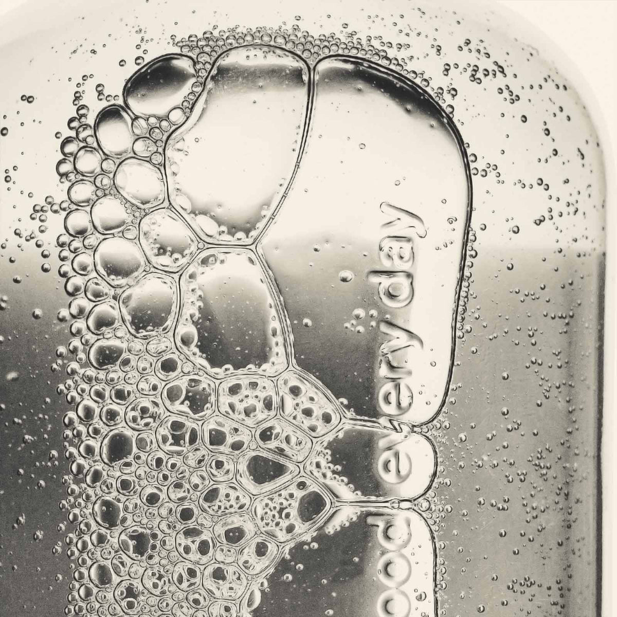 Foamy soap with 'good every day' imprinted on a glass surface.