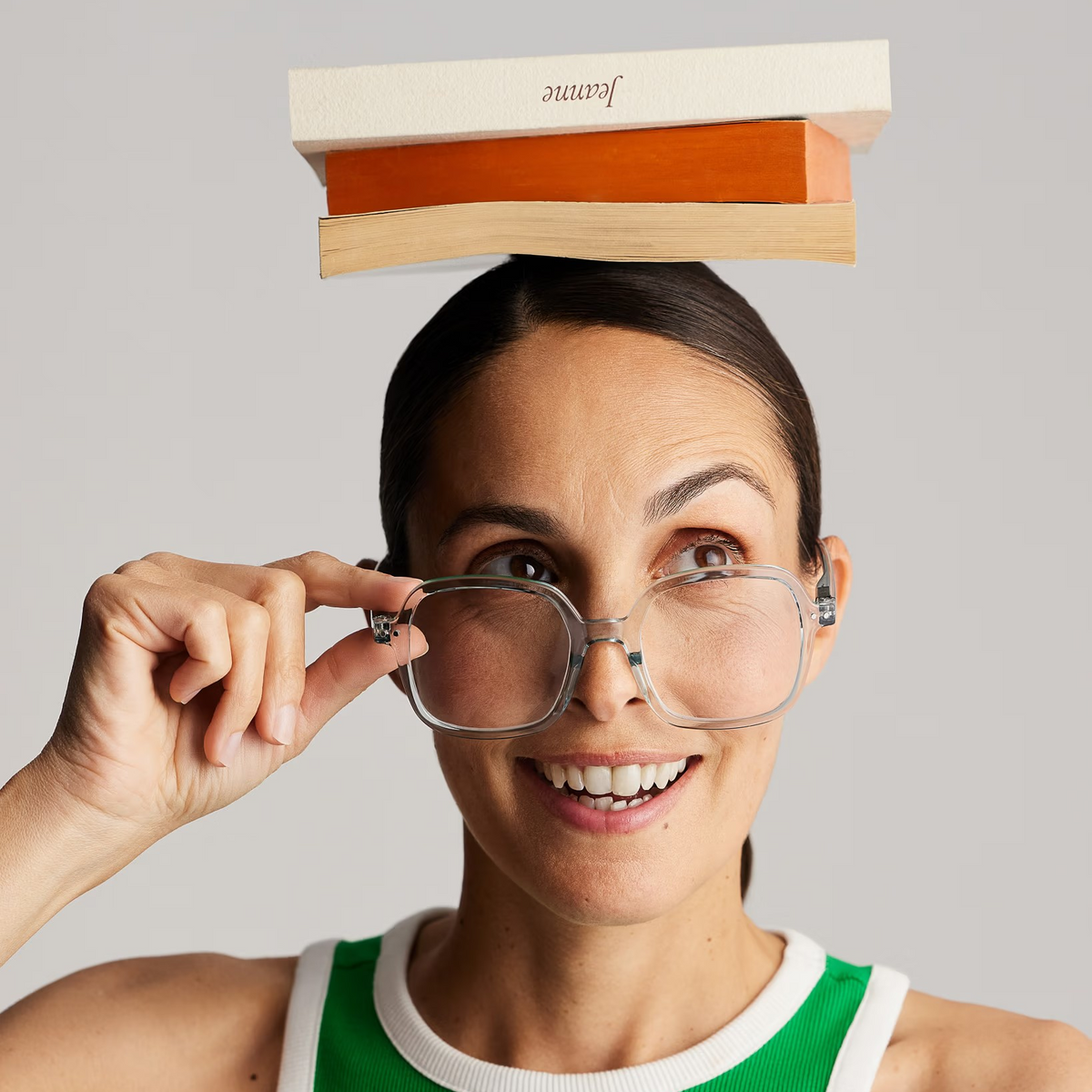 Woman wearing glasses with a box on her head, smiling against a plain background