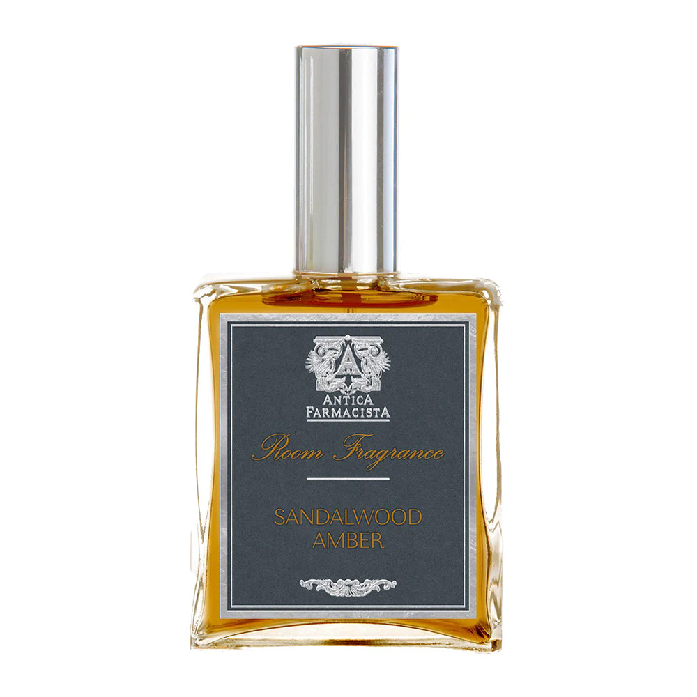 A glass bottle of Antica Farmacista Room Spray with a dark label displaying 'Sandalwood Amber' as the fragrance name.