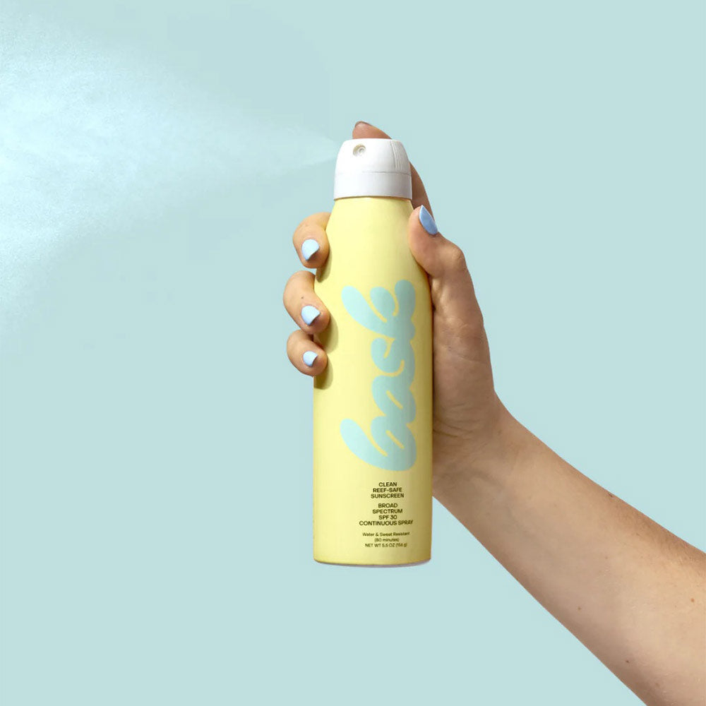 Hand spraying SPF 30 Non-Aerosol Continuous Spray - 5.5 oz on a blue background