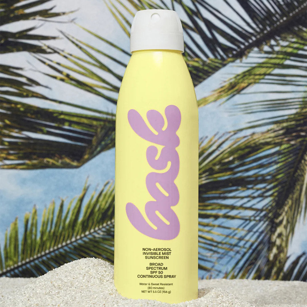Bask sunscreen on a sandy surface in front of images of palm trees