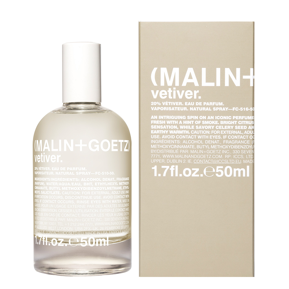 A clear glass bottle of MALIN+GOETZ vetiver Eau de Parfum with a white cap, shown next to its beige cardboard packaging box on a plain white background.
